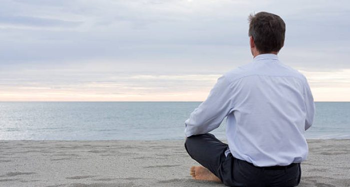 Businessman meditating on a beach at the sea Clay Tangner Therapy